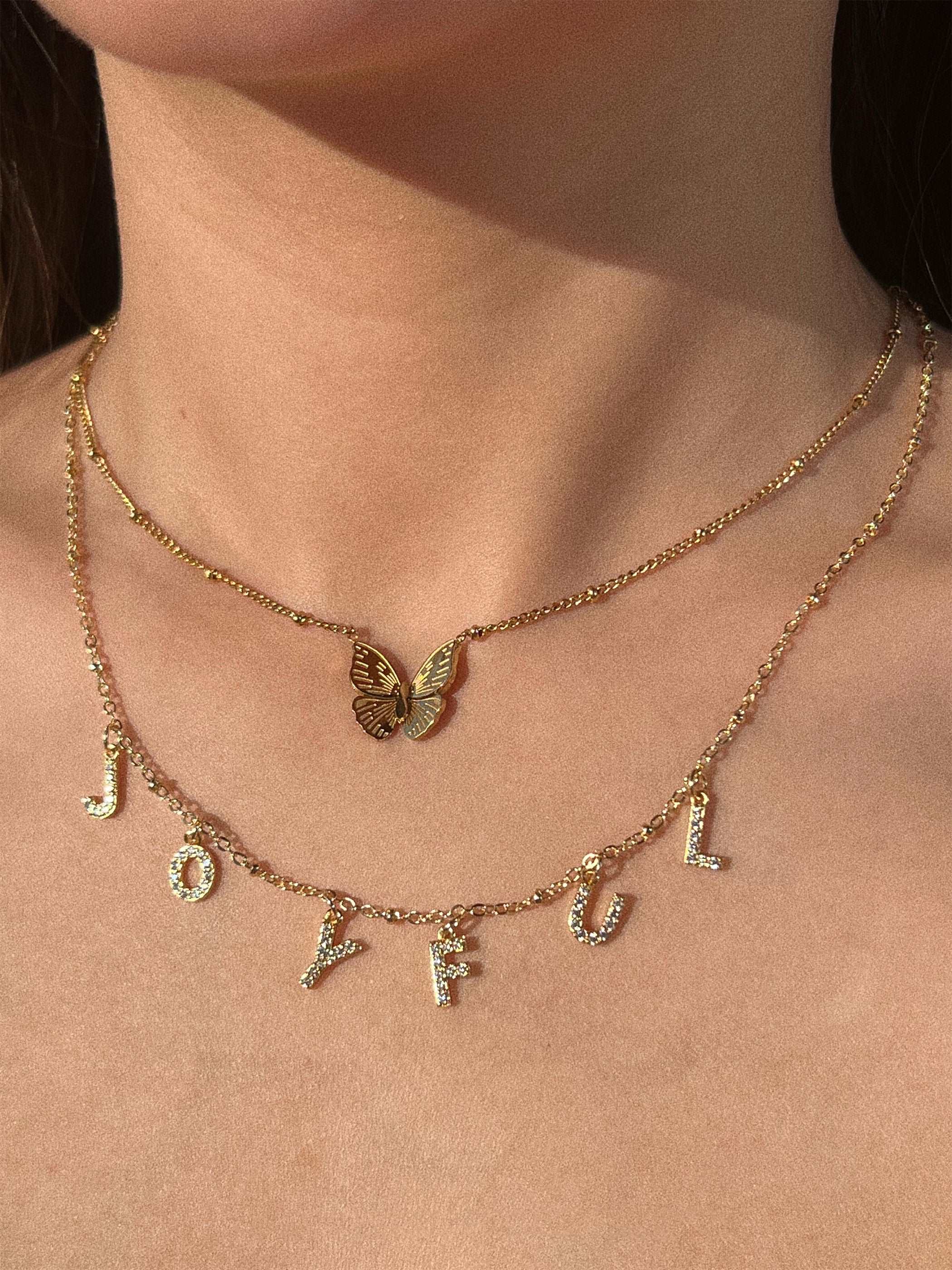 wearing Custom Roxy Letter Necklace and gold butterfly necklace