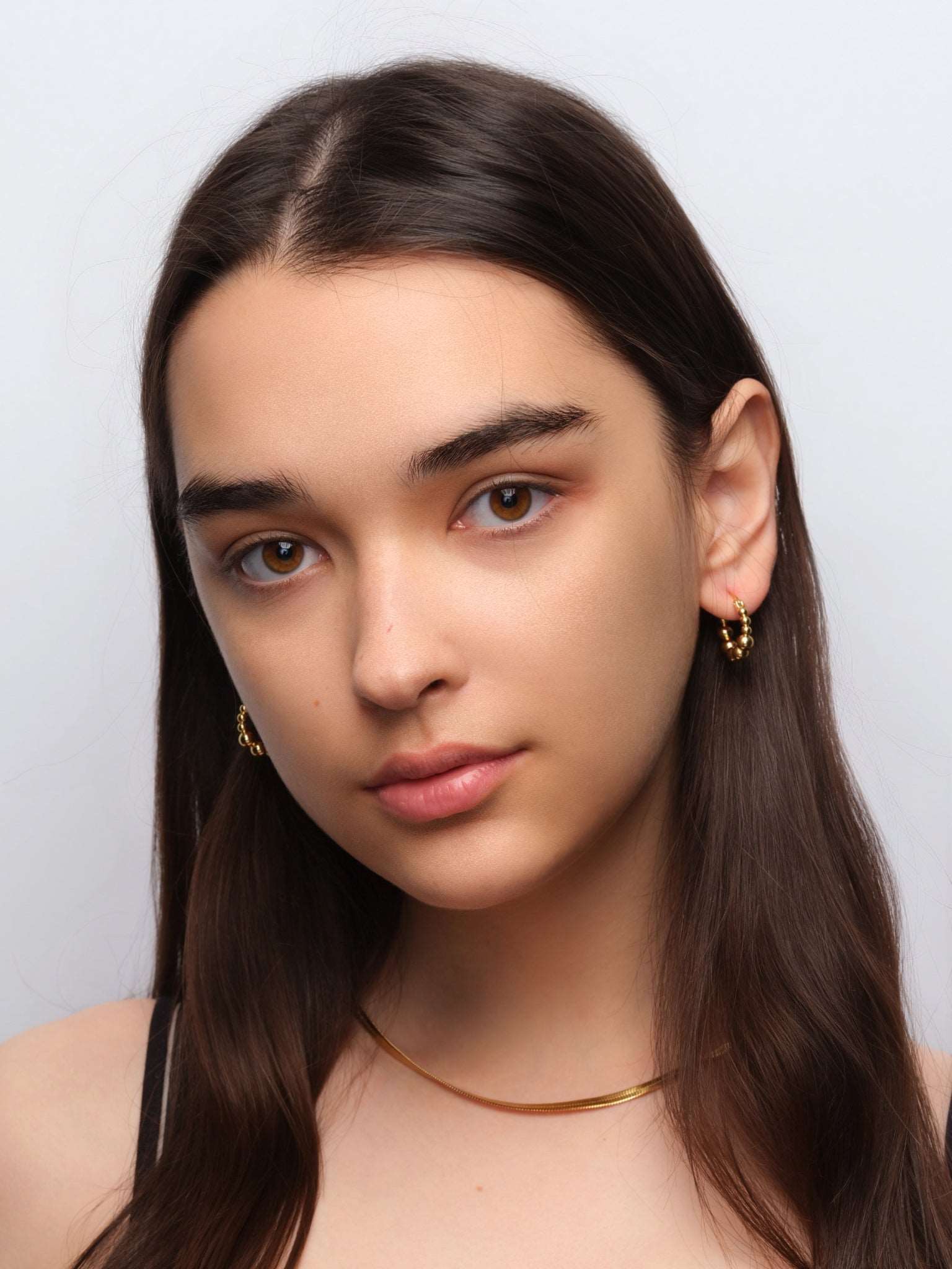 wearing Emery Gold Hoops and classic snake chain necklace